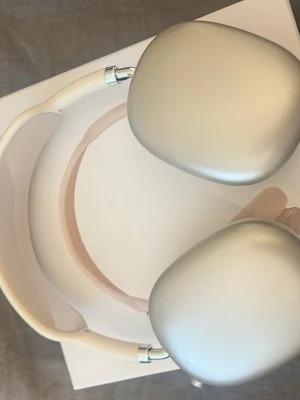 Apple AirPods Max guld hörlurar - Snygga Apple AirPods Max i guld med en stilren design. Hörlurarna har stora, ovala kåpor i aluminium och mjuka, vita öronkuddar i mesh-tyg. Bygeln är vadderad och justerbar för extra komfort. Perfekta för dig som vill ha grymt ljud och modern look.