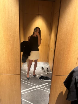 Svartvit kortklänning med smala axelband  - Snygg svartvit kortklänning med smala axelband och rak passform. Överdelen är svart och kjoldelen vit, vilket ger en stilren kontrast. Perfekt för dig som gillar minimalistisk och modern stil.