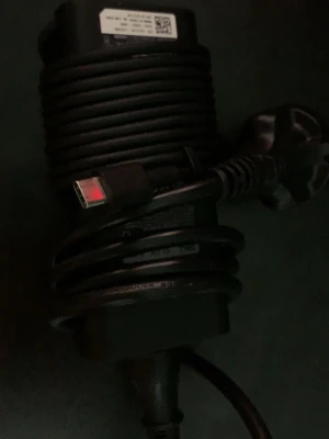 Dell USB-C laddare till laptop - Säljer en svart Dell USB-C laddare för laptop. Laddaren har en robust, cylinderformad design med tydlig Dell-logga och lång kabel. Perfekt för dig som behöver extra strömadapter till din dator eller vill ha en reservladdare.