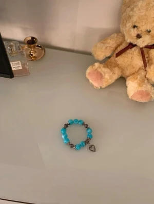 Vintage, turkost pärlarmband med hjärthänge - Sötaste vintage armbandet! Armbandet har turkosa och silverfärgade pärlor. Armbandet har ett sött hjärthänge som ger en personlig touch. Perfekt accessoar för att liva upp din outfit med lite färg och charm.