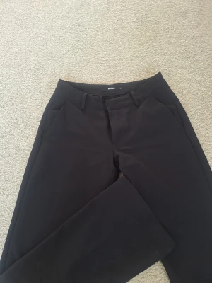 Svarta kostymbyxor från Bik Bok - Snygga svarta kostymbyxor från Bik Bok med raka ben och klassisk passform. Byxorna har hällor för skärp, sidofickor och stängs med dragkedja och hake. Perfekta för en stilren look och passar till många olika outfits. Det har är i superbra skick!