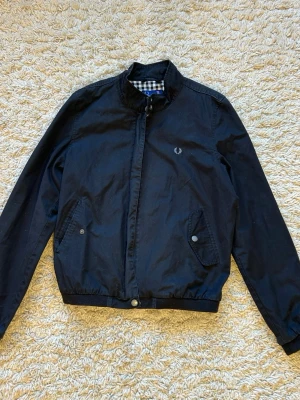 Fred Perry jacka - Säljer en riktigt snygg svart Fred Perry jacka som tyvärr är för liten för mig, köpt second hand. Normala tecken på slitage, men inga tydliga skavanker. Passar XS/S
