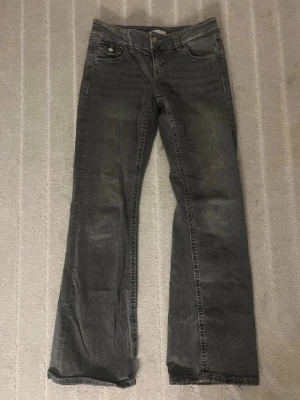 Grå bootcut jeans från Ginatricot - Säljer ett par grå bootcut jeans från Ginatricot. Fint skick förutom att knapparna förlorat färg. Storlek 158