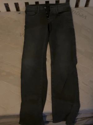 Svarta jeans från G-Star RAW 28/32 - Säljer ett par svarta jeans från G-Star RAW i storlek 28/32. Jeansen har raka ben, klassisk femficksdesign och knäppning med knappar. Perfekta för dig som gillar en clean och stilren look.