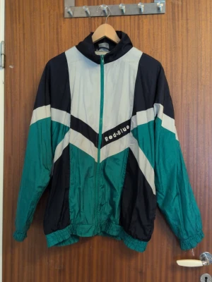 Retro vindjacka från Red-Blue - 90 tals vind/skaljacka, lätt fodrad inuti med tunt tyg, luftig å skön passform. Osäker på storleken då det inte står något men tänker runt Herr M? Lagom oversized på mig som dam s/m
