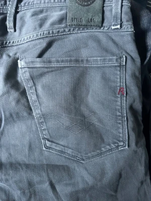 Grå jeans från Replay - Snygga grå jeans från Replay med klassisk femficksdesign och diskret logga på fickan. Jeansen har raka ben och är tillverkade i ett mjukt bomullsmaterial med lite stretch för extra komfort. Perfekta för en avslappnad och trendig look.