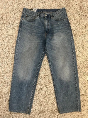 Levi's 568 mörkblå 34/32 - Klassiska blå jeans från Levi's med vid passform och fem fickor. Jeansen har en snygg tvättad look och är tillverkade i slitstark denim. Perfekta för en avslappnad och trendig stil. Storlek 34/32
