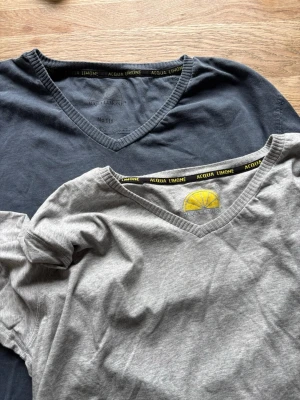 2 V-ringade t-shirts Acqua Limone - Två stilrena t-shirts från Acqua Limone, en i mörkblått och en i ljusgrått. Båda har v-ringad hals och klassisk passform. Tillverkade i mjuk bomull med flera snygga detaljer. Perfekta för en avslappnad look. Storlek XL