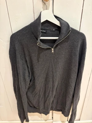 Mörkgrå stickad tröja Jack & Jones - Mörkgrå stickad tröja från Jack & Jones med halv dragkedja och hög krage. 