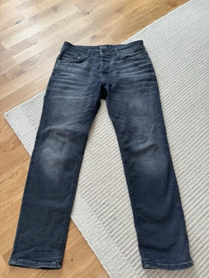 Mörk gråa jeans från Jack & Jones - Snygga mörkgråa jeans från Jack & Jones med passform slim/straight. Dem är i storlek 30/30.