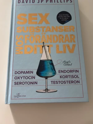Sex substanser som förändrar ditt liv - En inspirerande bok av David JP Phillips om sex viktiga signalsubstanser som påverkar hur vi mår: dopamin, oxytocin, serotonin, endorfin, kortisol och testosteron. Hård pärm i ljusblå färg med guldtext och illustration av ett kemiglas. Perfekt för dig som vill förstå och optimera din hjärna.