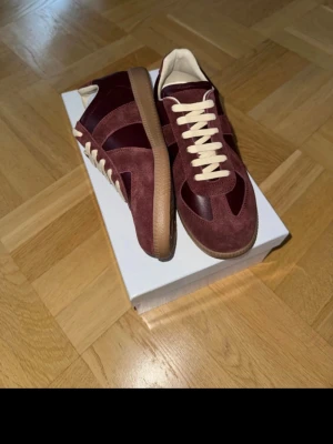 Vinröda sneakers i mocka och läder - Snygga sneakers i vinröd mocka och läder med beige snörning och gummisula. Klassisk låg modell med stilren design som passar perfekt till streetwear eller casual outfits. Skorna har en retrovibe och är riktigt lätta att matcha med olika looks.