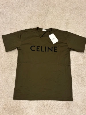 Olivgrön t-shirt från Cline - Snygg olivgrön t-shirt från Cline med svart logotyptryck framtill. Klassisk rund halsringning och korta ärmar. Perfekt för en stilren och trendig look.