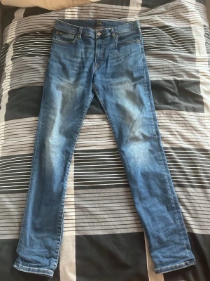 Blå slim fit jeans från Ralph Lauren  - Snygga blå slim fit jeans från H&M med klassisk femficksdesign och lätt slitna detaljer framtill och baktill. Jeansen har normal midja och smala ben, perfekta för en trendig och avslappnad look.