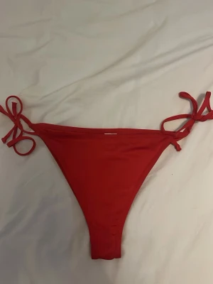 Röda bikiniunderdelar med knyt - Snygga röda bikiniunderdelar med knyt i sidorna. Klassisk triangelbikini i storlek S !! TVÄTTAS INNAN !!
