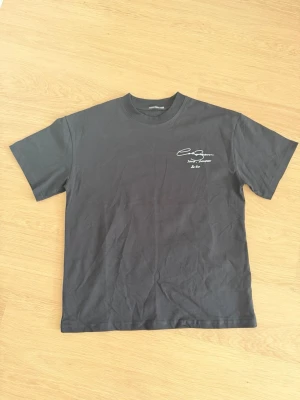 Svart t-shirt från Cole Buxton - Snygg svart t-shirt från Cole Buxton med vit textdetalj på bröstet. Klassisk passform med rund hals och korta ärmar. Tillverkad i mjuk bomull som känns skön mot huden. Perfekt för en clean och stilren look.