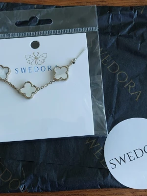 Diana fyrklöver armband Swedora guldfärgat och vitt - Helt nytt och ouppackat armband från Swedora med vita fyrklöverformade länkar och guldfärgad kedja.