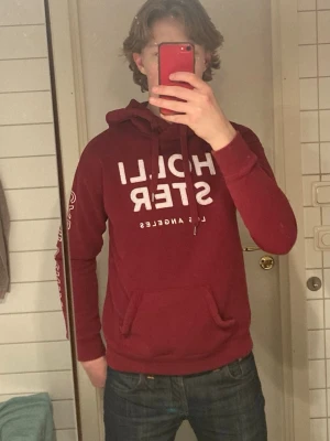 Vinröd hoodie från Hollister - Säljer en Hollister Hoodie i mycket bra skick! Tröjan har inga defekter och är sparaamt använd. Storlek S, personen på bilden är 180 cm och väger 65 kg, Hör av er om frågor!
