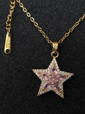 Guldhalsband med stjärnhänge och pärlor - Snyggt guldhalsband i rostfritt stål med ett stjärnformat hänge dekorerat med små vita pärlor och rosa stenar i mitten. Kedjan är tunn och har justerbar längd. Perfekt för dig som vill ha något glittrigt och unikt till din stil. 45 cm 