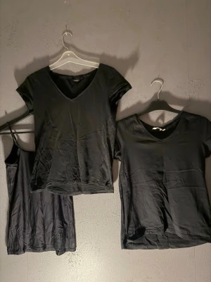 Svarta toppar och linne i bomull - Säljer ett set med två svarta t-shirts med v-ringning och ett svart linne med smala axelband. Alla tre plagg är i mjuk bomull och har enkel, stilren design. Perfekt bas till garderoben.