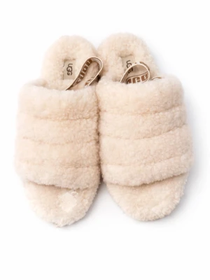 Beige fluffiga tofflor från UGG - Mysiga beige tofflor från UGG med öppen tå och breda band i fluffigt fårskinn. Sulan är i gummi med UGG-logga och mönster för bra grepp. Tofflorna har en elastisk rem med UGG-tryck för extra support. Perfekta för chill hemma eller när du vill ha det extra bekvämt.