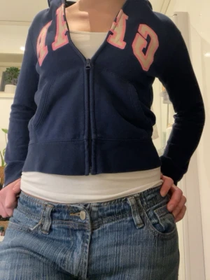Mörkblå hoodie från GAP med dragkedja - Snygg mörkblå hoodie från GAP med dragkedja. Ganska bra kvalitet. Själv har jag xs i hoodie och denna har lite korta ärmar för mig. Ärmen är 47 cm och bysten är 41 cm