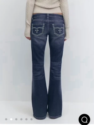 Bootcut jeans med slitningar - Mörkblå bootcut jeans med slitningar på knäna och framsidan. Snygga kontrastsömmar och broderade bakfickor. Klassisk femficksmodell i denim med lite stretch för skön passform.