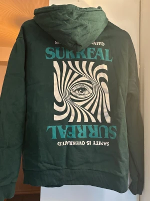 Hoodie - Mörkgrön hoodie från Madlady med tryck på baksidan. Hoodien har huva med snören och en klassisk magficka framtill. Tillverkad i mjukt bomullsmaterial. Hoodien är i mycket fint skick🤍 Storleken är XS men oversized i storlek då den passar mig som bär vanligtvis S😊