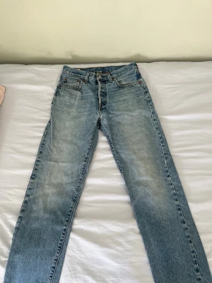Levi's Premium raka blå jeans - Säljer ett par klassiska raka blå jeans från Levi's Premium. Jeansen har fem fickor, bälteshällor och en snygg tvättad look med ljusblå nyans. Perfekta till vardags och passar till det mesta. Materialet är slitstark denim i bomull.