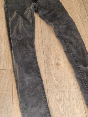 Grå slim fit jeans från Replay - Snygga grå svarta  slim fit jeans från Replay med klassisk femficksdesign och metallknapp med logga. Jeansen har en tvättad look och smal passform som ger en modern vibe. Perfekta för dig som gillar stilrena och bekväma jeans i slitstarkt denim.