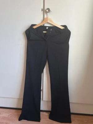 Svarta kostymbyxor med utsvängda ben - Säljer ett par svarta kostymbyxor från Nelly. Jag själv är 156 cm lång och de är lite för långa för mig. Har haft på mig de 2-3 gånger. 
