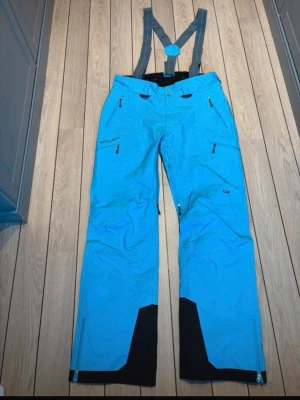 Skidbyxor Stellar Equipment  - Skalbyxor från Stellar Equipment med hängslen och hällor för skärp för skönaste passformen.  W Stellar Shell Pants. Färg: Aqua Storlek: Large Nypris 3500kr