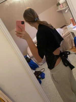 Svart topp med öppen rygg och knyt - Säljer en svart topp med öppen rygg och knyt i midjan. Toppen har korta ärmar och en stilren, enkel framsida. Perfekt för dig som vill ha en trendig och unik detalj på din outfit.