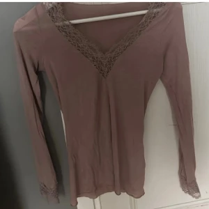Intimissimi tröja  - Mysig ljusbrun långärmad topp med spetsdetaljer vid V-ringningen och ärmsluten. Perfekt för chill dagar hemma. Tunn och mjuk kvalitet som känns skön mot huden.