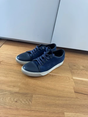 Mörkblå sneakers i mocka och läder - Snygga mörkblå sneakers med ovandel i mocka och tåparti i slätt läder. Skorna har vita sulor och matchande mörkblå skosnören. Perfekta för dig som gillar en stilren och enkel look. Passar till jeans och kostymbyxor för en avslappnad  men ändå uppklädd vibe mvh// Lukas