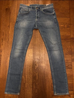 Blå dondup George jeans - Snygga blå slim fit jeans från dondup med klassisk femficksdesign och lätt slitna detaljer. Modellen heter George. Jeansen har normal midja och smala ben, perfekta för en trendig och avslappnad stil. Tillverkade i stretchigt denim för extra komfort. Perfekt passform och tvätt, kolla in profilen för fler liknande par!