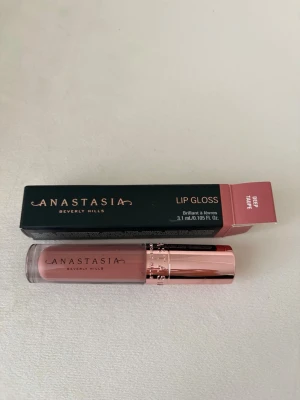 Anastasia Beverly Hills Lipgloss Deep Taupe - Snyggt läppglans från Anastasia Beverly Hills i färgen Deep Taupe. Kommer i en stilren tub med roséguldfärgat lock och transparent hylsa som visar den mjukt brunrosa nyansen. Perfekt för dig som vill ha glansiga och fylliga läppar.