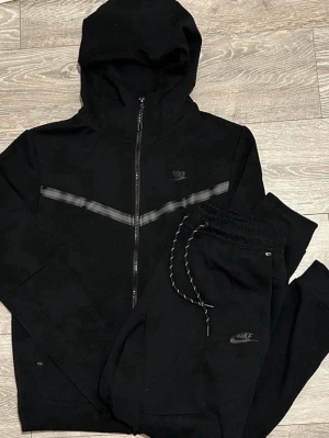 Svart Nike Tech Fleece set - Nike Tech Fleece set i svart med matchande hoodie och byxor.  Helt ny med taggar o kvitto som medföljer