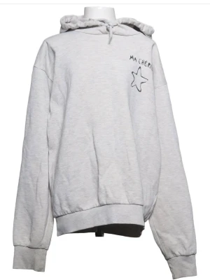 Grå hoodie med tryck  - Ljusgrå hoodie. På bröstet och ryggen finns ett svart tryck med texten Je M’en Amor och en stjärna. är inte exakt en sån som på första och andra bilden, men väldigt lik. på snören. När ska du sitta en liten metallgrej den har tyvärr åkt av men tröjan är perfekt att ha så myströja jätteskön och faktiskt väldigt snygg. Säljer på grund av att det inte kommit till användning. pris går att diskutera(speciellt om man köper mer saker från mig) 