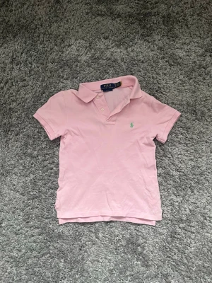 Rosa pikétröja från Polo Ralph Lauren - Klassisk rosa pikétröja från Polo Ralph Lauren i storlek S Barn säljs för 200kr!