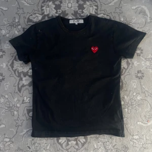 Svart t-shirt från Comme des Garçons - CDG - Säljer en svart t-shirt från Comme des Garçons med det ikoniska röda hjärtat broderat på bröstet. Stilren och sparsamt använd med inga synliga defekter! Passar dig runt 170-180!  
