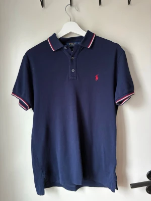 Marinblå pikétröja från Polo Ralph Lauren - customfit - small - Säljer denna snygga Polo Ralph lauren piké i storlek Small!☀️Den är i mkt bra skick nästintill ny! Den har en fin marinblå färg med snygga detaljer vid armen samt kragen. Priset är diskutabelt vid en snabb affär! Fråga vid funderingar! ☺️Skickas snabbt 📦 finns massa andra artiklar uppe på min profil eller följ mig för kommande släpp!🚀