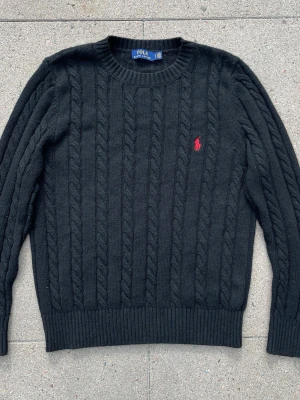 Svart ralph Lauren kabelstickad tröja - Säljer en Svart ralph Lauren kabelstickad tröja i storlek M! Inga skador på den pga att den är inte använd så mycket, den är för liten för mig så vill helst bli av med den så fort som möjligt, skriv om ni har några funderingar eller prisförslag så kan vi komma överens om något!!