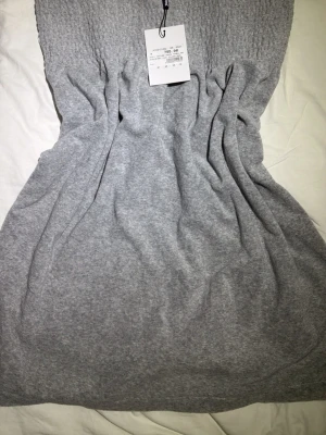 Juicy Couture Klänning - Helt ny, oanvänd mjuk och skön grå klänning från Juicy Couture med smockad överdel och axelband. Klänningen är perfekt för chill dagar eller för en mysig ute kväll på sommaren. Materialet är stretchigt för extra komfort och skulle även kunna passa för dig som har storlek L. Prislapp är kvar! Öppen för prisförslag men var gärna vettiga😇 