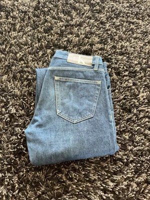 Blå jeans från Calvin Klein - Säljer ett par klassiska blå jeans från Calvin Klein med raka ben . Jeansen har fem fickor, silverfärgade nitar och logga på bakfickan samt etikett i midjan. Tillverkade i slitstark denim som passar perfekt till alla tillfällen. Hör av er vid frågor! 
