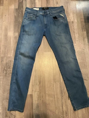 Replay jeans  - Säljer ett par blå slim fit jeans från Replay, modell Anbass. Jeansen har klassisk femficksdesign, snygga slitningar och raka ben. Perfekta för dig som gillar en smalare passform och vill ha ett par stilrena jeans till garderoben. Knappt använda säljs för jag växt ur dom 