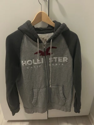 Grå zip-hoodie från Hollister - Säljer denna snygga Zip-Hoodien ifrån Hollister. Storlek S, men passar M med. Nytt skick, knappt använd. Snabbare affär-bättre pris!