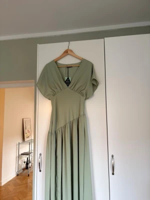 Ljusgrön långklänning  - Snygg ljusgrön klänning (helt ny med lapp kvar). Perfekt för sommarens alla tillfällen. Storlek 34.