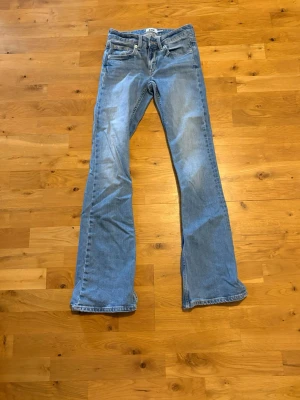 Ljusblå bootcut jeans från Lager 157 - Säljer ett par ljusblå bootcut jeans från Lager 157 med klassisk femficksmodell och dragkedja. Jeansen har en avslappnad passform med utsvängda ben och är tillverkade i denim. Perfekta för en cool och avslappnad stil. 💗💗🥹