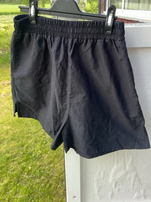 Svarta shorts från djerf avenue - Svarta shorts från djerf avenue med elastisk midja och avslappnad passform. Tillverkade i ett lätt tyg, perfekta för varma dagar. Shortsen har en låtsas bakficka. Klassisk och enkel design som funkar till det mesta.